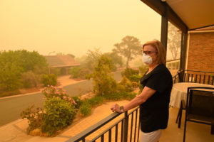 A woman, on a balcony, wears a face mask to protect herself against very dangerous level of air pollution created by nearby wildfires